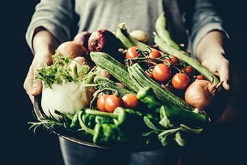 A photo of a basket of vegetables held in a persons arms